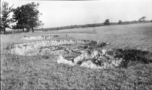 <b>Caption:</b>  Surface breaks in a field near Carterville, 300 yards SW of <!--LINK'" 0:11--> The shaft is 120 feet deep and a 7 foot bed of coal is being mined. The roof is slate and the overburden is clay; no quicksand has been noted. The breaks are about 20 feet in diameter and from a few feet to as much as 20 feet deep.<br><b>Credit:</b>  Illinois State Geological Survey<br><b>Date:</b>  Pre-1914<br><b>Publication:</b>  Fig. 12 Cooperative Bulletin 17 – Subsidence in Illinois<br><b>Library No.:</b>  M-991