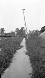 <b>Caption:</b>  Broken sidewalk and telephone poles tipped toward a sag over Franklin Count Mine where and 8 foot coal is being removed at a depth of 450 feet.<br><b>Credit:</b>  Illinois State Geological Survey<br><b>Date:</b>  Pre-1914<br><b>Publication:</b>  Fig. 26 Cooperative Bulletin 17 – Subsidence in Illinois<br><b>Library No.:</b>  M-825
